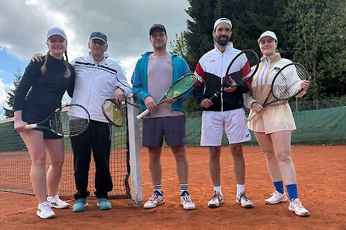 Ein Tennistrainer steht mir zwei weiblichen und zwei männlichen Spielern am Netz Hubert Herzig mit vier Tennisspielern